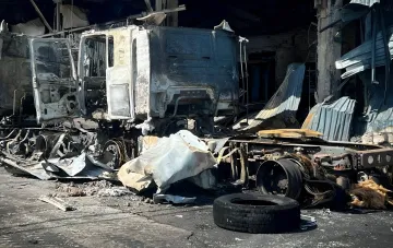 Сгоревший грузовик на фоне разрушенного здания после ударов по Киеву и области 28 августа