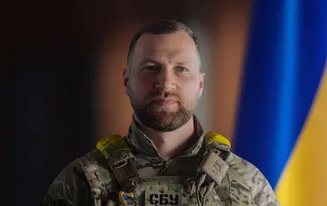 Militär in Uniform mit SBU-Aufnäher vor der ukrainischen Flagge — Bild zum Thema, dass Chmara das Team des Verteidigungsministeriums behält und mit Fjodorow verhandelt