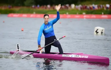 Lyudmyla Luzan in the Ukraine national kit waves to spectators in her kayak after winning gold at the 2026 World Rowing Championships