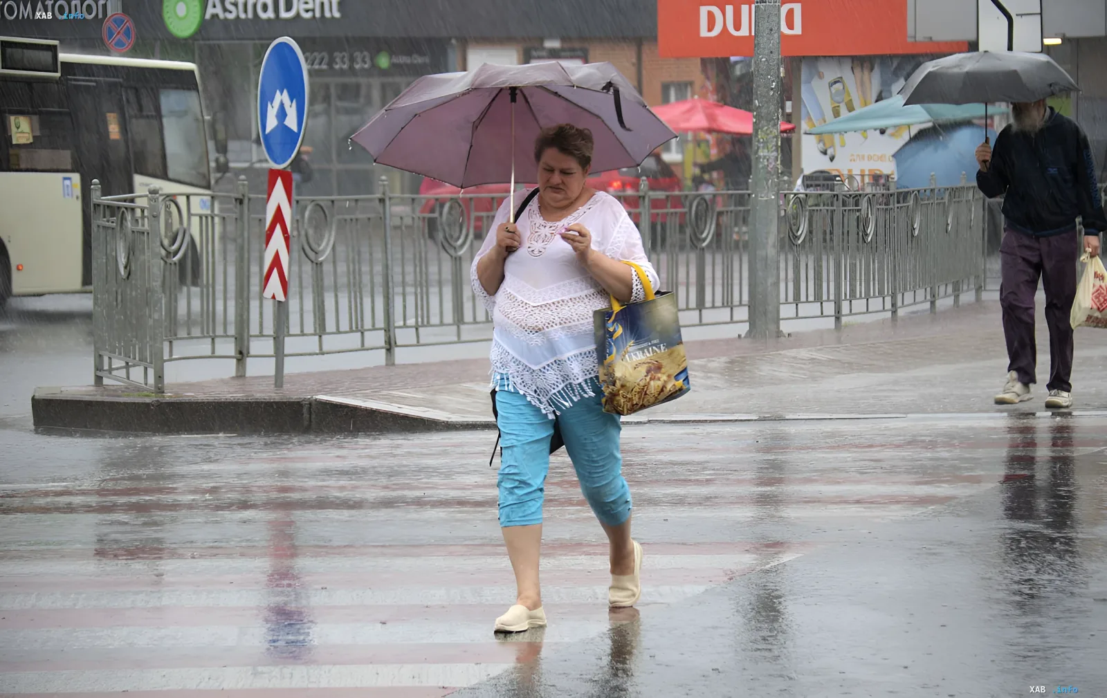 Pedestrians with umbrellas cross a wet street in rainy weather in Ukraine