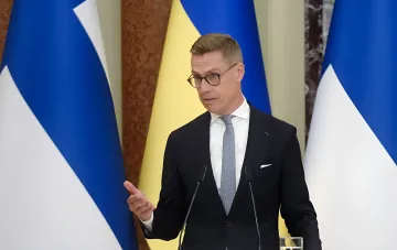 Президент Финляндии Алексантер Стубб выступает за трибуной на фоне флагов Финляндии и Украины, заявляя о роли Украины в безопасности Европы