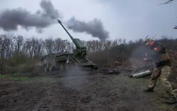 Украинский военнослужащий наблюдает за выстрелом самоходной гаубицы 155-мм калибра на полигоне