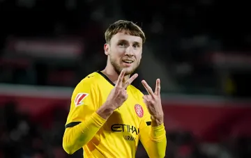 Ukrainian player Vanat in a yellow Girona kit celebrating after his assist in the La Liga match against Las Palmas, making a distinctive hand gesture