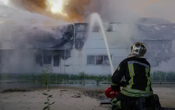 Пожарний гасить будівлю, постраждалу внаслідок атаки на Київ і область 31 серпня