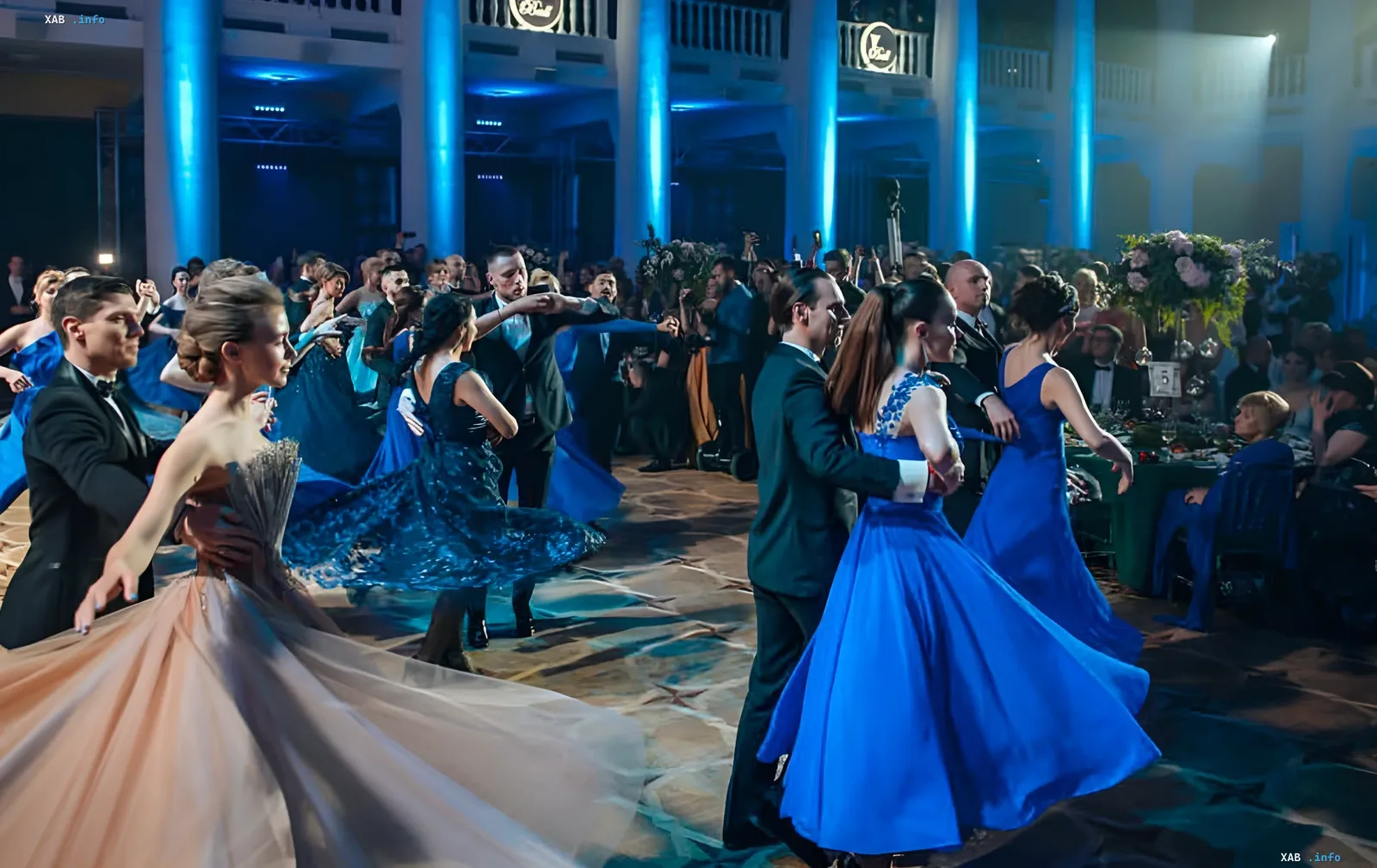 Пара танцует парадный вальс на Charity Viennese Ball во Львове: женщина в пышном кремовом бальном платье и мужчина в смокинге в роскошном зале с люстрами