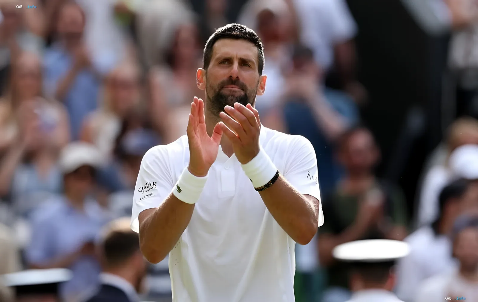 Новак Джокович в белой форме хлопает в ладоши на корте US Open после сенсационного поражения в первом круге