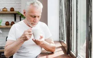 A man holds a cup of milk and looks at it thoughtfully — illustration for the topic of genetic lactose intolerance and gluten sensitivity