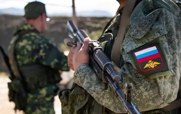 Российский военнослужащий с автоматом на фоне проверки индонезийских граждан в армии России