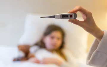 Цифровой термометр в руке врача на фоне больной девочки: цифровизация медицинских услуг в Украине без очередей