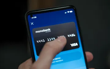 A user taps a smartphone screen showing the monobank app with a virtual VISA card — illustrating the new kids feature 'Ask parents for money'