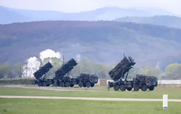 Пусковые установки зенитно-ракетного комплекса Patriot на полигоне с наклонёнными контейнерами для ракет на фоне гор