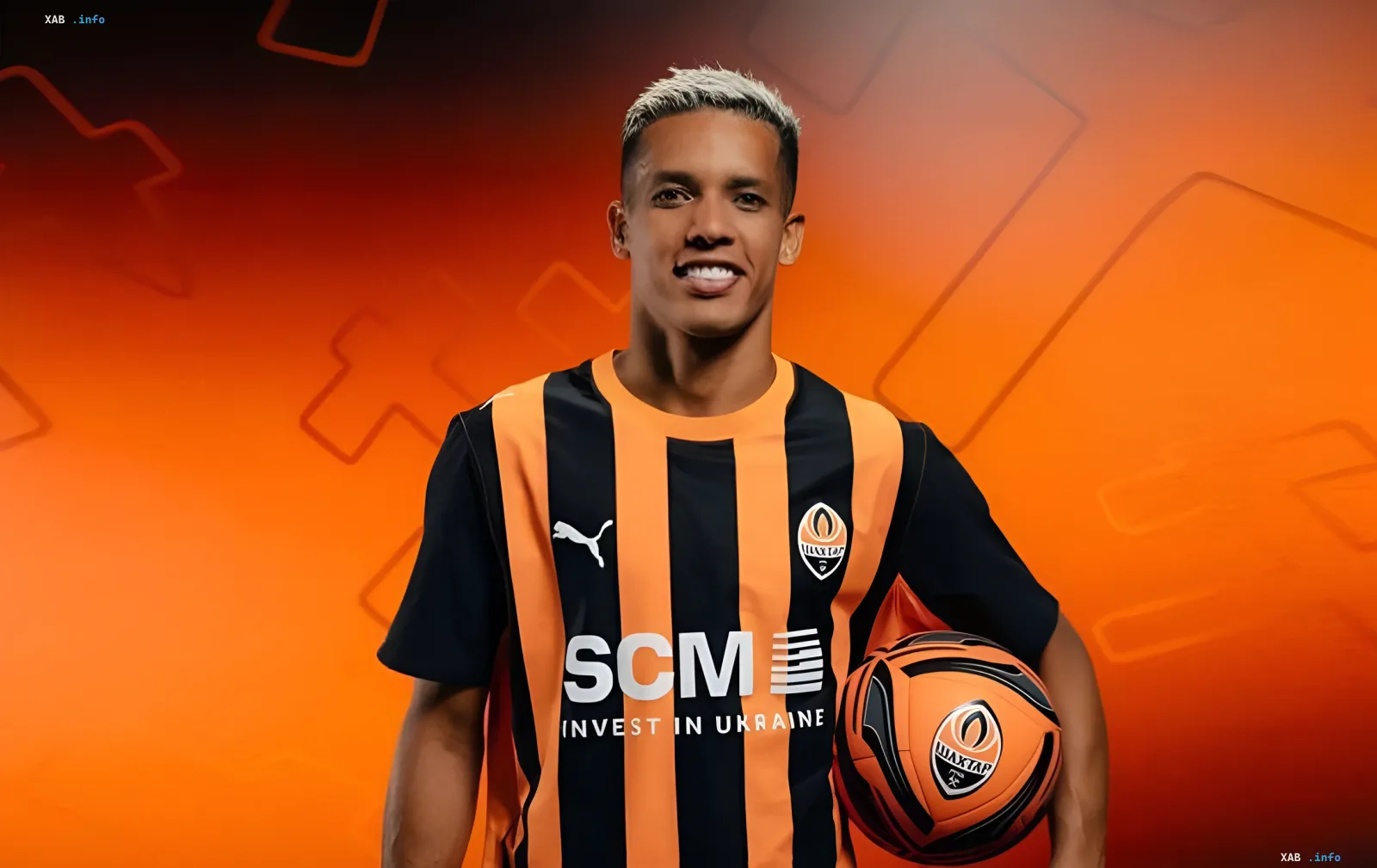 FC-Schachtar-Spieler im Trikot mit SCM-Logo und Invest in Ukraine-Slogan vor orangefarbenem Hintergrund