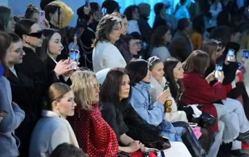 Publikum bei einer Show der Ukrainian Fashion Week SS27 in Kiew: stilvolle Gäste filmen den Laufsteg mit Smartphones