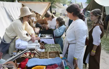 Handwerkermarkt in traditioneller Tracht: Eine Bewohnerin eines ukrainischen Karpatendorfs zeigt Gästen handgefertigte Produkte auf einem ethnografischen Tourismusfestival im Rahmen des UN-Status Best Tourism Villages