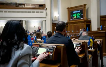 Abgeordnete der ukrainischen Werchowna Rada an ihren Arbeitsplätzen mit elektronischen Abstimmungssystemen im Parlamentssaal; ein „Plan B“ für die Stimmabgabe per Telefon im Keller bei Luftalarm wird diskutiert