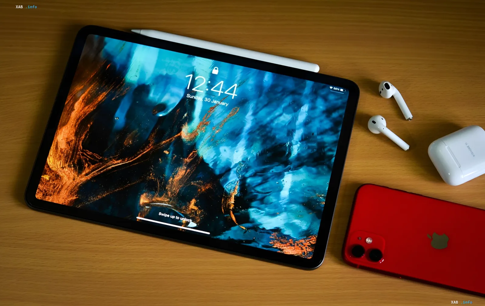 Екосистема Apple: планшет iPad, AirPods 5 і червоний iPhone на дерев'яному столі — осінні новинки Apple 2026