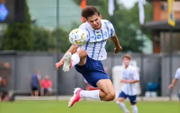 A Dynamo U-19 player in the white and blue kit jumps to control the ball in a UEFA Youth League match against Rangers