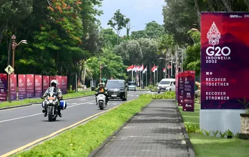 Баннер G20 Indonesia 2022 с лозунгом Recover Together Recover Stronger на фоне дороги и флагов Индонезии — иллюстрация к теме саммита G20 и условий экономического сотрудничества с Россией