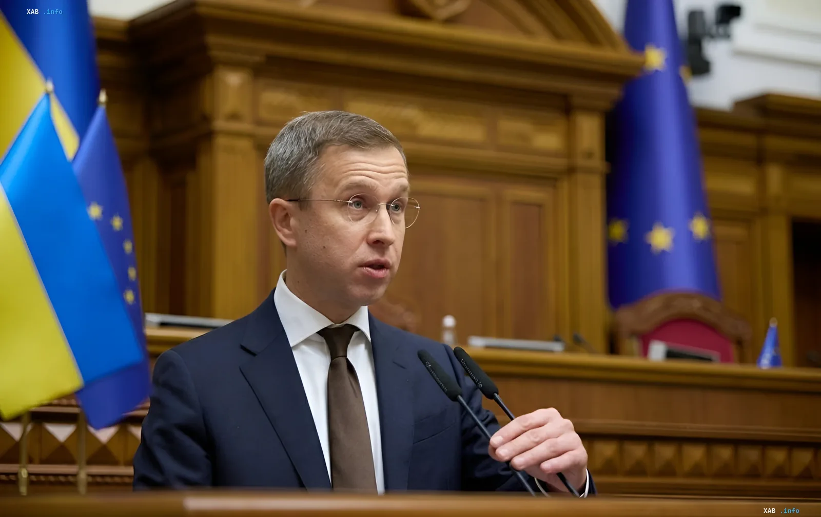 Speech at a podium against Ukrainian and EU flags in the context of strict budget austerity and closing the state budget deficit