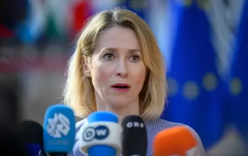 Кайя Каллас на прес-конференції перед мікрофонами європейських ЗМІ на тлі прапора ЄС, закликаючи передати Україні ракети-перехоплювачі з вичерпним терміном придатності