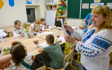 Учительница показывает работу ученика в классе в первый день нового учебного года в Украине