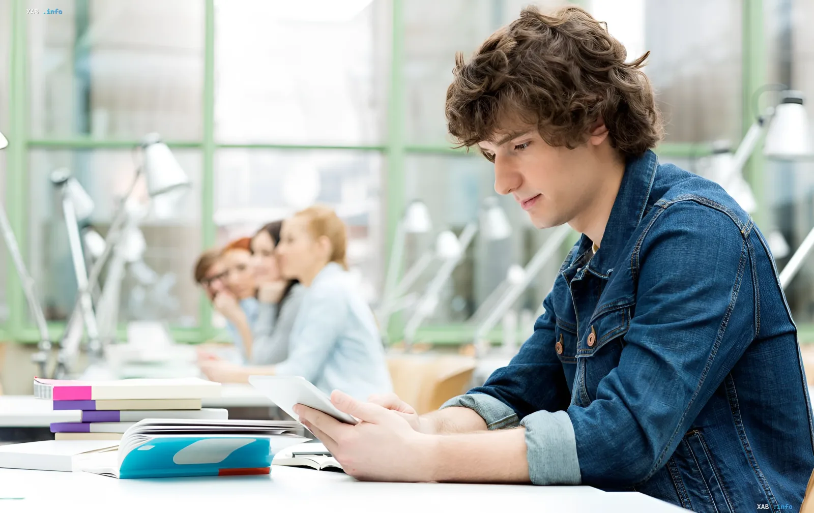 Student with a tablet and textbooks at a desk in a Ukrainian university classroom at the start of the new academic year