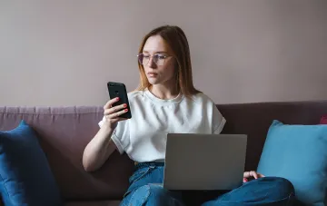 Frau mit Laptop und Smartphone sammelt Online-Spenden für wohltätige Zwecke über PrivatBank