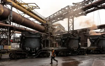 Ukrainian industrial site: coal-loaded mine carts, pipes and a worker in a safety vest — a symbol of an industry needing comprehensive support