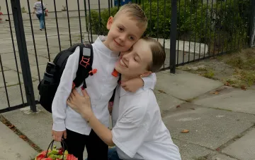Ukrainische Prominente umarmt ihren Sohn mit Rucksack und Blumenstrauß am ersten Schultag, 1. September 2026