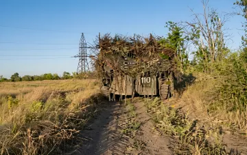 Camouflaged Russian armored vehicle marked 110 in a field near power lines — drone footage from the 7th Cossack Corps