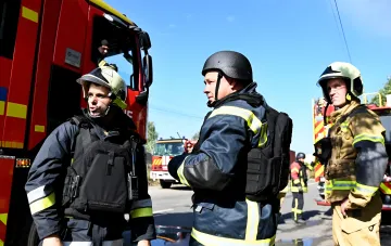 Feuerwehrleute in Schutzausrüstung an Feuerwehrfahrzeugen nach einem Drohnenschlag auf ein Sechsstöckiges Gebäude im Schevtchenkowskyj-Bezirk von Kiew