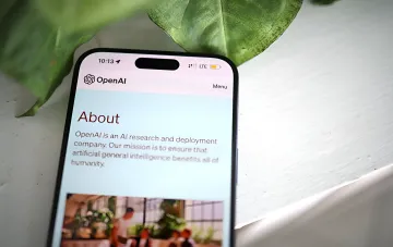 Смартфон с открытым сайтом OpenAI на фоне зелёных листьев — компания готовит ИИ-модель Astra для поиска zero-day уязвимостей