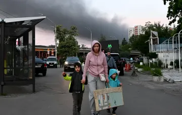 Женщина с двумя детьми на улице Киева под тёмным небом во время воздушной тревоги из-за дронов