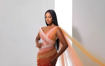 Miss Uganda in einem mehrschichtigen Pfirsichkleid bei Miss World, das die sieben Schichten eines Kaiserschnitts symbolisiert