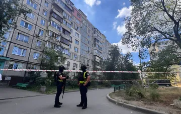 Вооружённые сотрудники в тактической экипировке у оцепления на фоне жилого дома в Киеве во время перестрелки между СБУ и ГУР