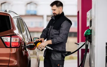 Водій заправляє автомобіль на АЗС на тлі новин про подорожчання палива в Україні на 1 гривню