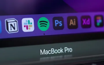 Иконки Slack и Photoshop в доке MacBook Pro — визуализация интеграции инструментов Adobe в мессенджер
