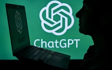 Пользователь за ноутбуком с логотипом ChatGPT на фоне крупного знака сервиса во время глобального сбоя ИИ-чат-ботов