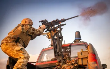 Soldat mit einem montierten Maschinengewehr auf einem Fahrzeug im Kampf bei Drohnenangriffen auf Kiew