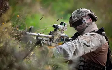 Soldat der ukrainischen Nationalgarde in Tarnkleidung mit Waffenzieloptik in einem Feldversteck in Richtung Charkiw bei Kupjansk