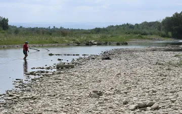 Shallow river in Ukraine with a wide gravel bar during low water season, a person walking through the low water