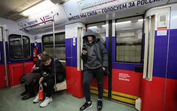 Пассажиры московского метро в вагоне с агитационными плакатами «Голосуем за Россию» и «Голосуй онлайн» перед выборами