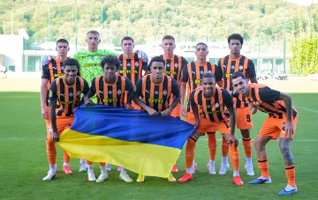 Игроки «Шахтера» в черно-оранжевой форме держат флаг Украины перед матчем Лиги чемпионов