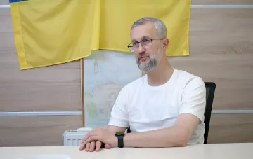 Посол Украины в Турции на фоне государственного флага Украины в кабинете