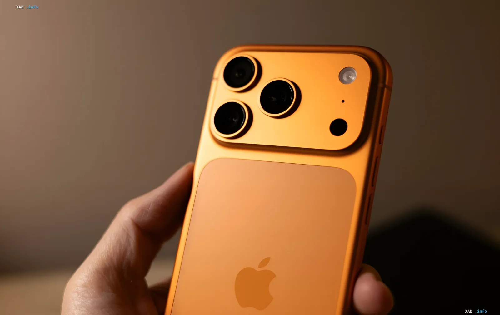 Оранжевый iPhone Pro с тройной камерой в руке — модель, которая подорожает на 10–20% из-за роста цен на память