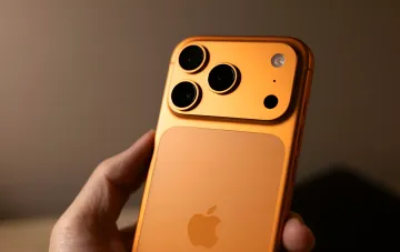 Оранжевый iPhone Pro с тройной камерой в руке — модель, которая подорожает на 10–20% из-за роста цен на память