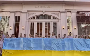 Mitarbeiter der Kiewer Konditorei Namelaka mit ukrainischer Flagge am Eingang nach Produktionsstopp wegen Salmonellen-Ausbruchs