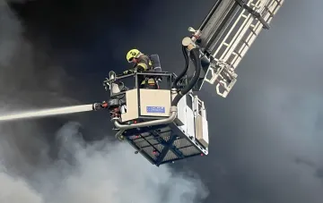 Feuerwehrmann auf einer Teleskopleiter löscht die Coca-Cola-Fabrik bei Kiew nach einem Drohnenangriff