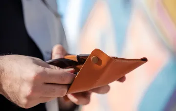 Hands holding an open leather wallet — a symbol of folk money superstitions and the bay leaf ritual for attracting wealth