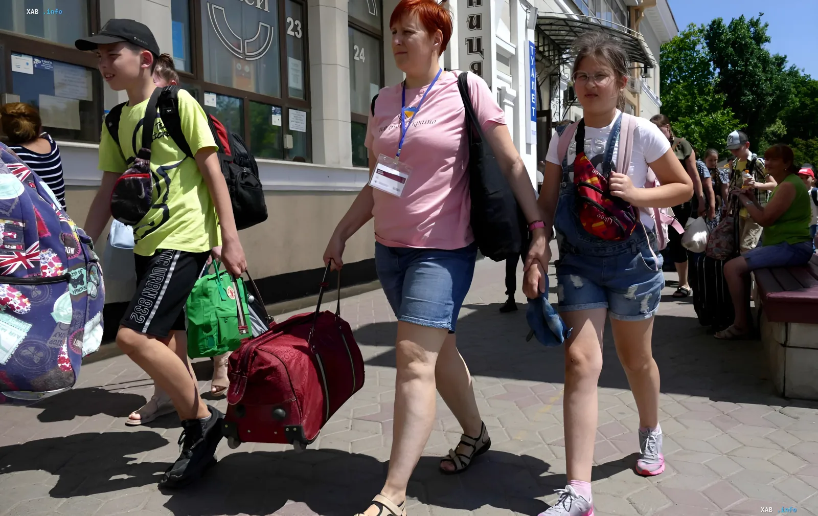 Семья внутренне перемещенных лиц с багажом на фоне здания театра в Украине